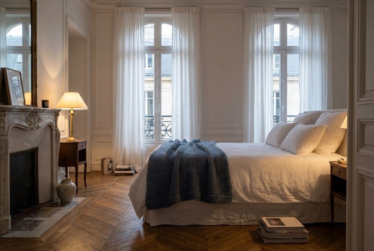 Chambre d'une résidence Worknest — literie hôtelière, cheminée en marbre, lumière douce